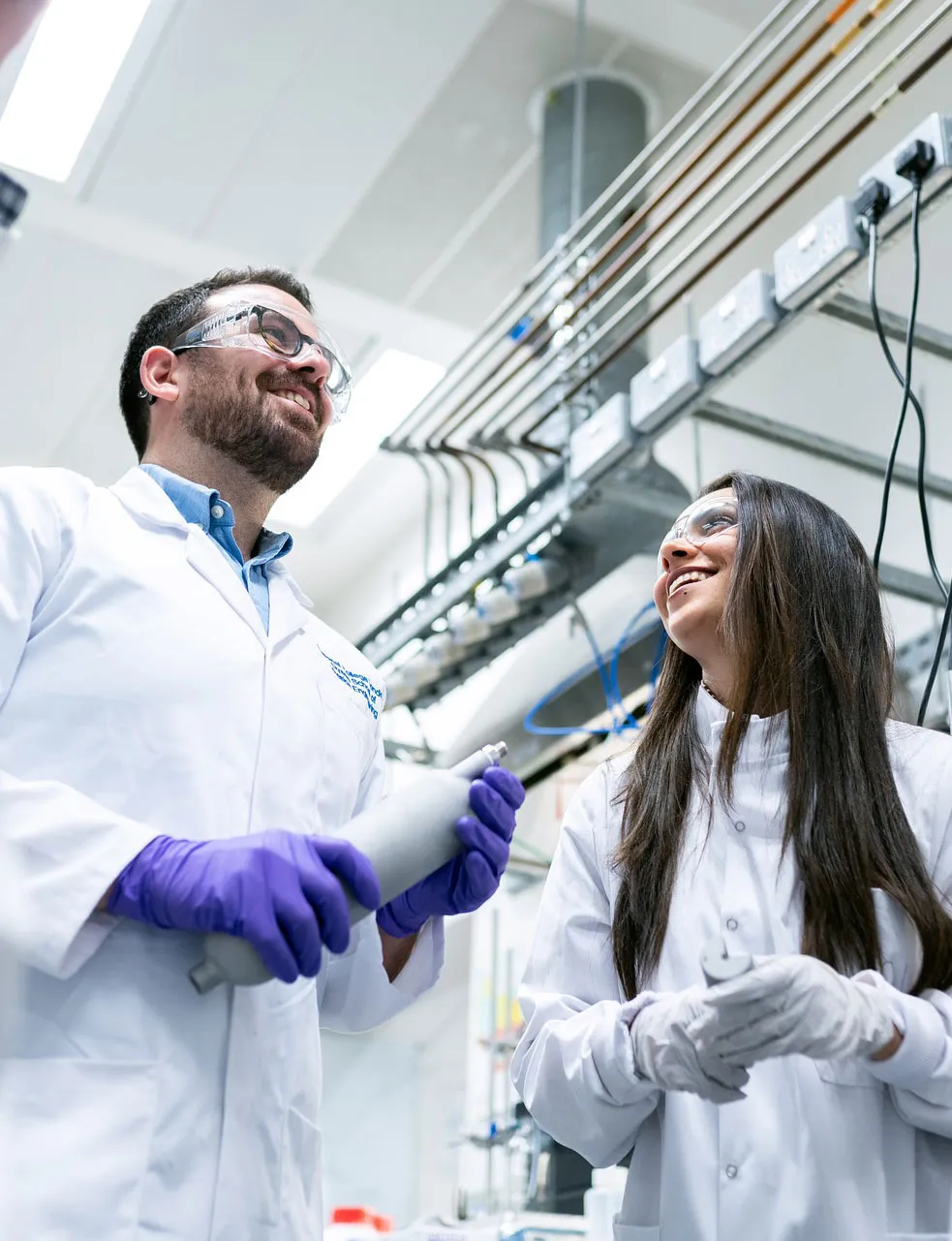 Two laboratory scientists in white coats talking in a lab